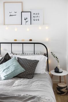 a bed with white sheets and pillows in a bedroom next to two pictures on the wall