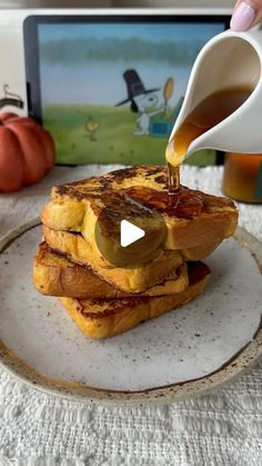 a person pouring syrup on top of some french toast sandwiches in front of an ipad