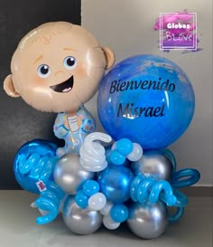 a balloon with a baby in it sitting on top of some blue and silver balloons