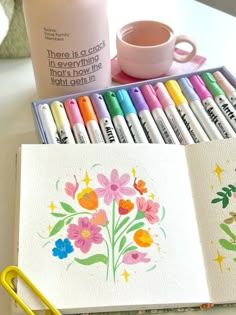 there are many markers and pens on the desk next to each other, including one with flowers