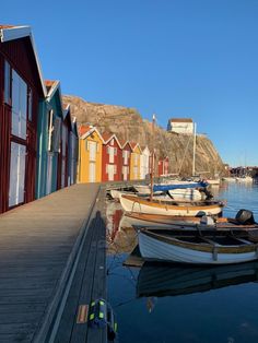 several boats are docked in the water next to colorful houses and cliffs on a clear day