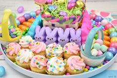 a plate filled with cupcakes, candy and candies next to an easter basket