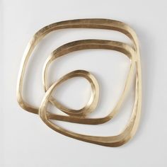 three brass rings on a white surface, one is shaped like a spiral and the other has