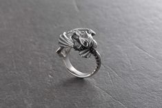 a silver ring with a dragon head on it's face and two claws in the middle