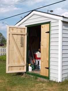 an outhouse with the door open and tools in the back yard area next to it