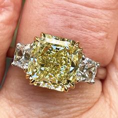 a fancy yellow diamond ring on someone's hand