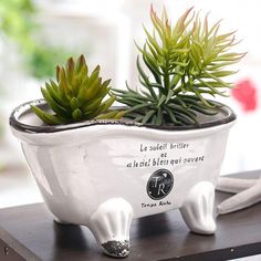 a white ceramic planter with succulents in it sitting on a table