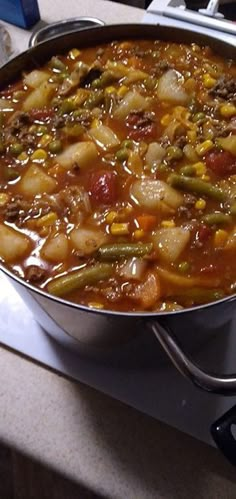 a pot filled with stew sitting on top of a stove next to a burner