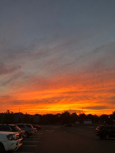 a parking lot filled with lots of parked cars under a cloudy sky in the distance