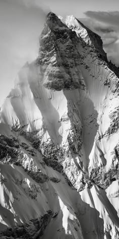 black and white photograph of the top of a snow covered mountain with clouds in the sky