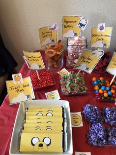 a table topped with lots of candy and candies on top of a red table cloth