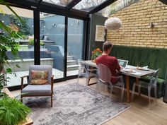 a man sitting at a table in front of a glass enclosed room with green couches