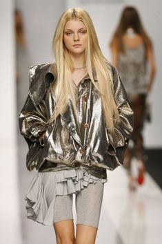 a model walks down the runway wearing silver clothes