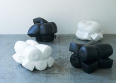 three black and white sculptures sitting next to each other on a cement floor in front of a white wall