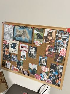 a bulletin board with pictures on it next to a laptop computer and other office supplies