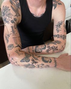 a man with tattoos sitting at a table