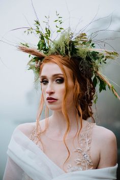 a woman with red hair wearing a white dress and flowers in her hair is looking off to the side