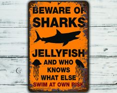 a sign that says beware of sharks jellyfish and who knows what else swim at own risk