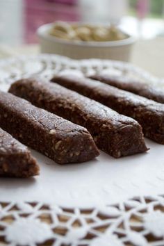 five brownies on a white doily next to a bowl of nuts