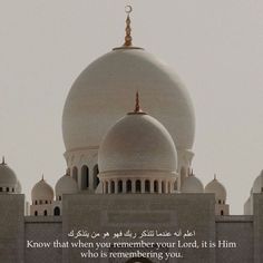 a large white building with two domes and a poem written in arabic on the front