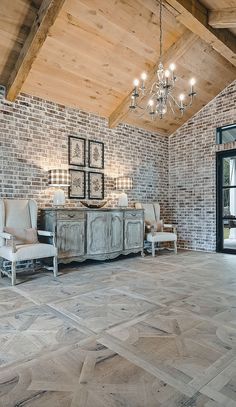 a living room with two chairs and a chandelier hanging from the rafters