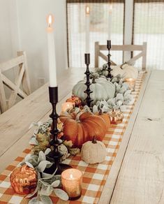 a long table with candles and pumpkins on it