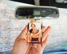 a person holding up a photo in front of a car mirror