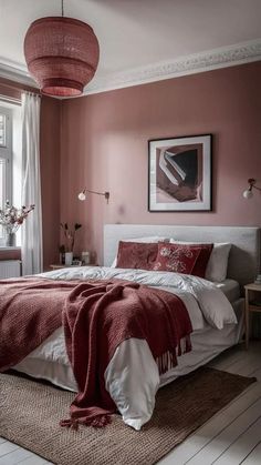 a bedroom decorated in pink and white with a large red blanket on the bed next to a window