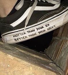 someone wearing black and white shoes with writing on the side of their shoelaces