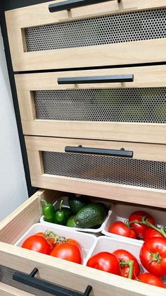 tomatoes, cucumbers and green peppers are stored in the bottom drawer of an open cabinet