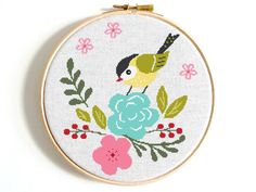 a cross stitch bird sitting on top of a flower