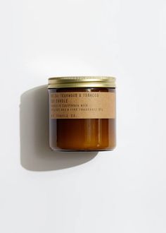 a jar of candle sitting on top of a white wall next to a brown label