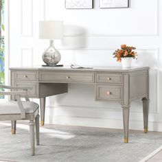 a gray desk with two chairs and a vase on it in front of a white wall