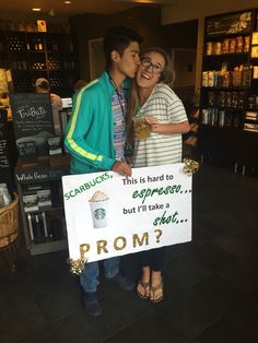 two people standing next to each other holding a sign