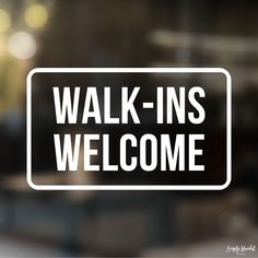 a sign that says walk - ins welcome in white on a glass door with blurry background