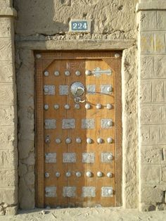 an old door with metal rivets and numbers on the side of a building