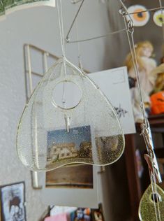 a bird feeder hanging from a ceiling in a room with pictures on the wall behind it