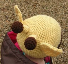 a small child wearing a crocheted hat with two brown buttons on it's ears