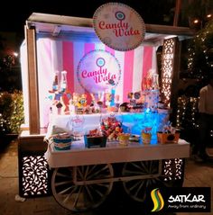 candy vendor cart at night with lights on the side and candies on display in front