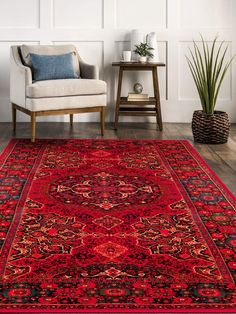 a large red rug with an ornate design on the floor in front of a chair