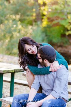 a man and woman sitting on a bench in front of a picnic table with pumpkins