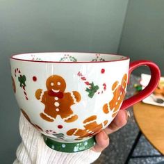 a person holding up a cup decorated with gingerbreads and candy canes on it