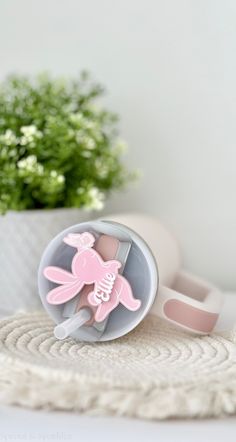 a pink unicorn brooch sitting on top of a white table next to a potted plant