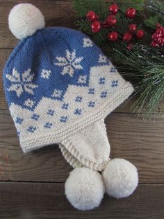 a knitted hat with snowflakes on it next to berries and pine needles