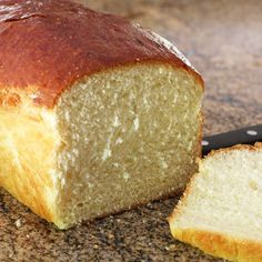 a loaf of bread sitting on top of a counter next to a slice of bread