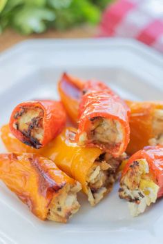 several stuffed peppers on a white plate ready to be eaten with cheese and other toppings