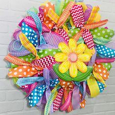 a colorful wreath hanging on the side of a brick wall with polka dots and flowers