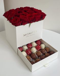 a white box filled with chocolates and roses