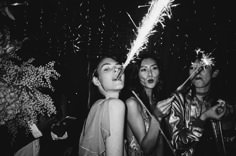 two women and one man are holding sparklers