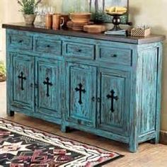 an old blue cabinet with crosses painted on the doors and drawers is in front of a rug